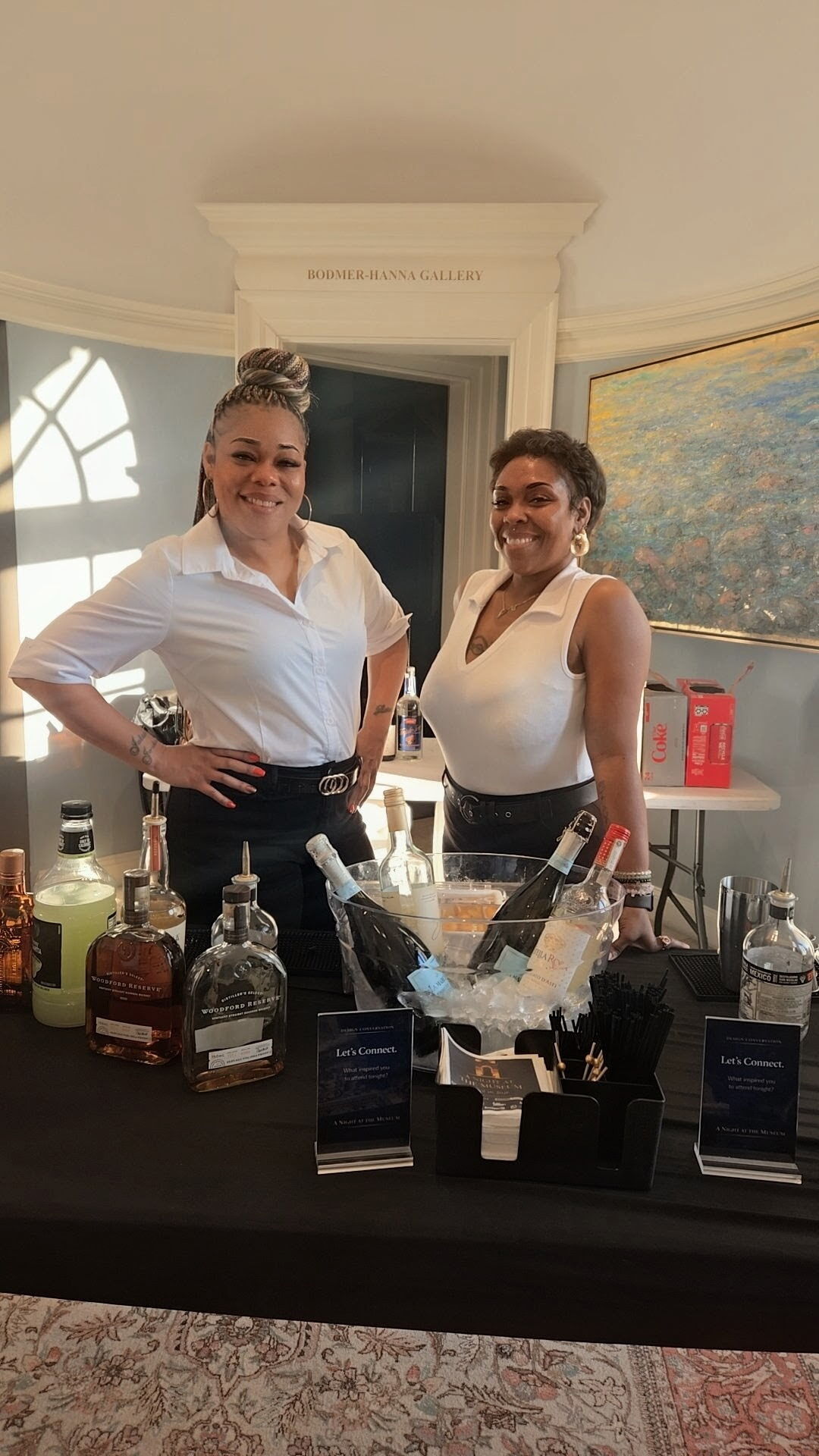 Two bartenders preparing bottles and tools for an event